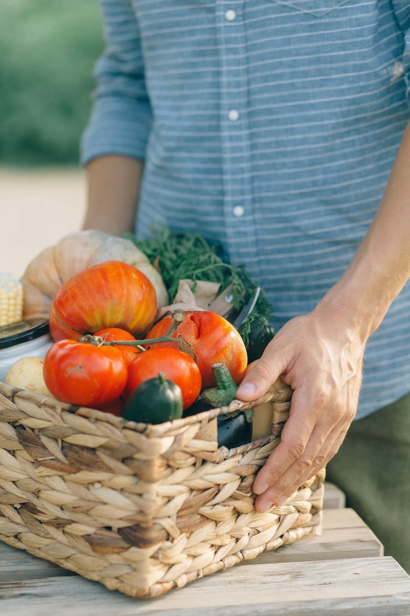 Vibrant collection of freshly harvested organic vegetables held in a wicker basket outdoors.